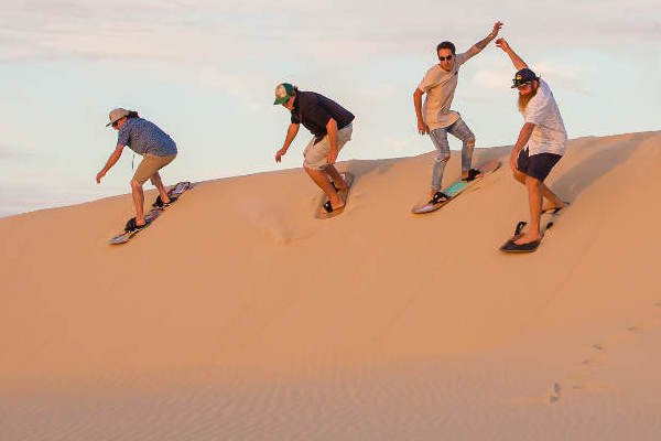 Sandboarding in the Sahara – action shot on golden dunes